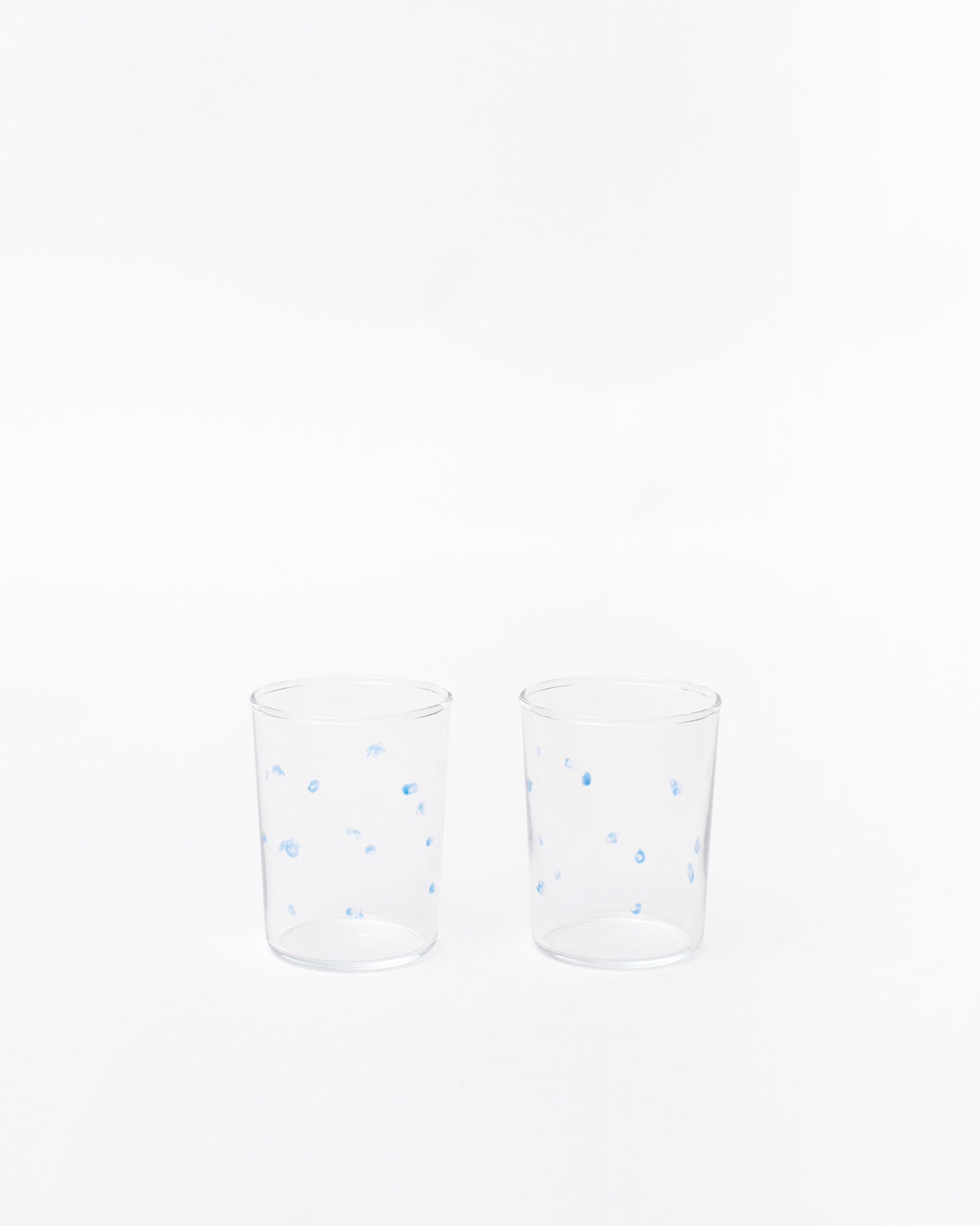 Two glasses with handmade dotted design next to each other on a white background