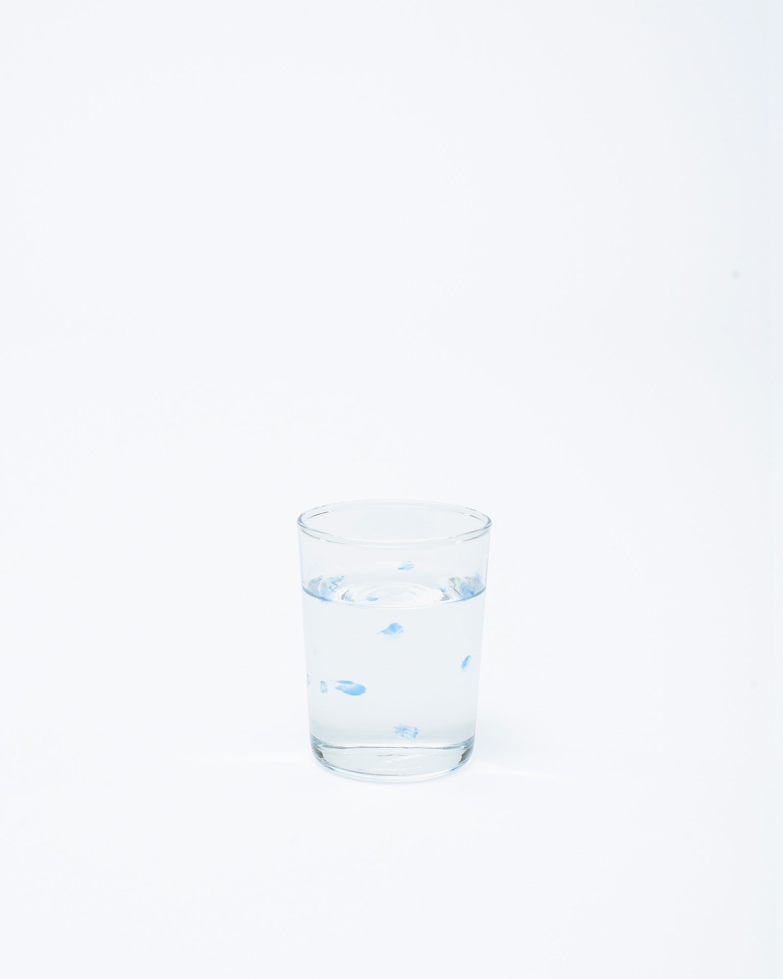 A glass with handmade dotted design in water on a white background.