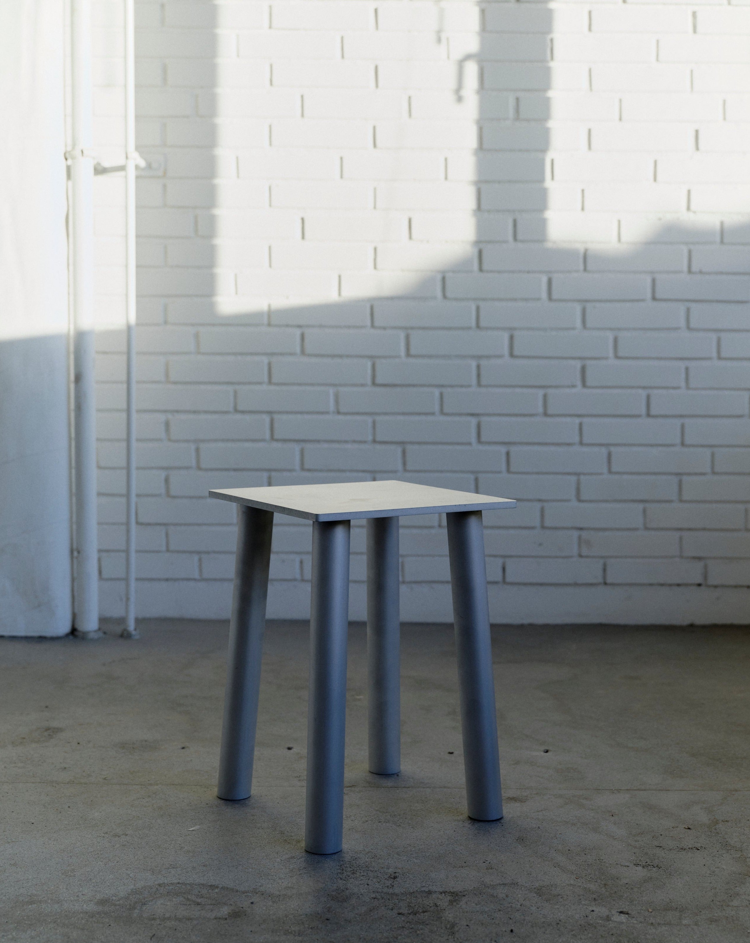 Decorative aluminum stool P-L series lying diagonally to the left in lifestyle background