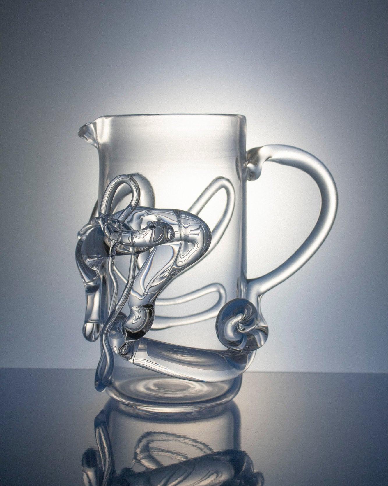 Glass pitcher with melted glass details with handle on right side on light focus background