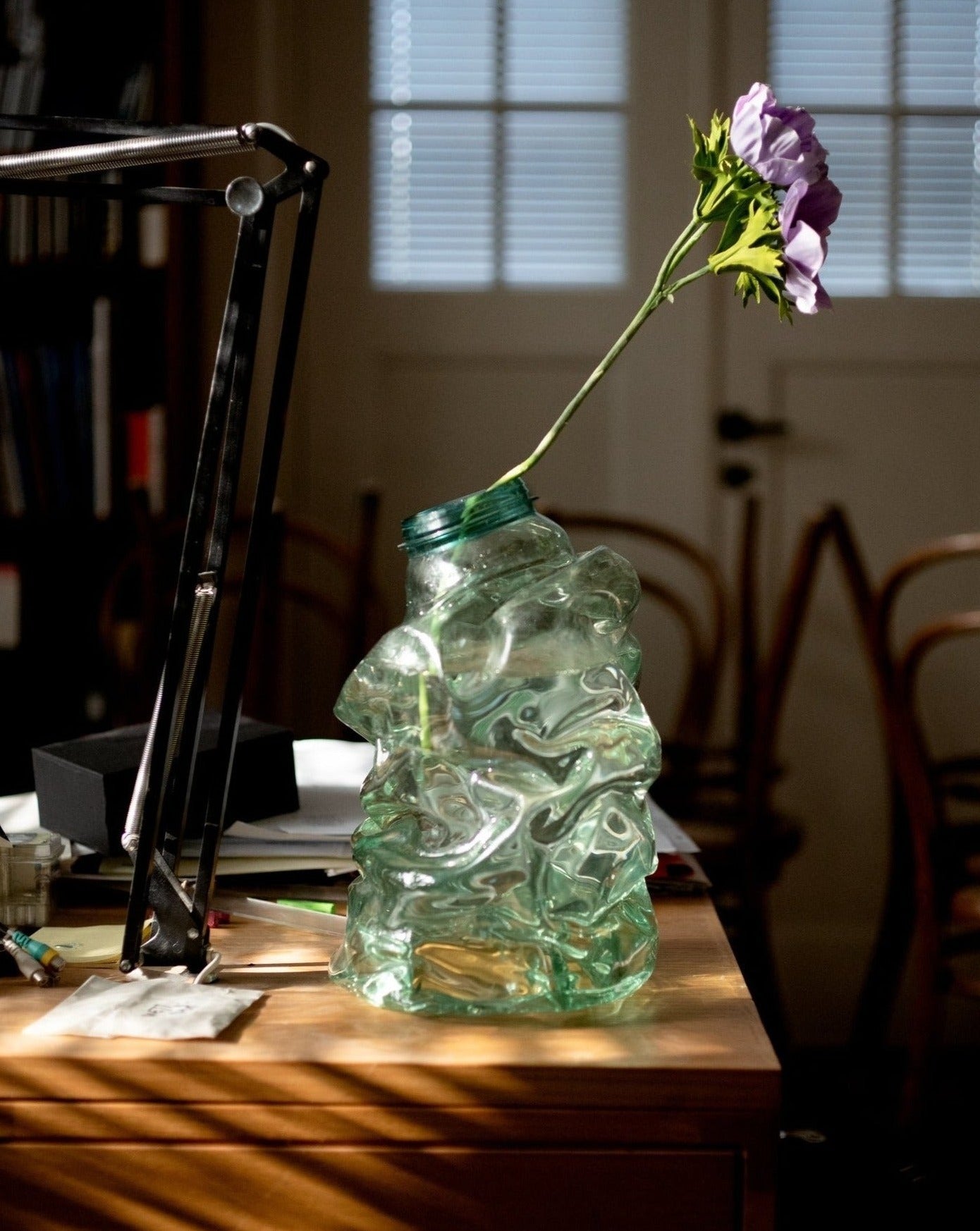 Large green handmade recycled plastic vase with pioneer flower on desk