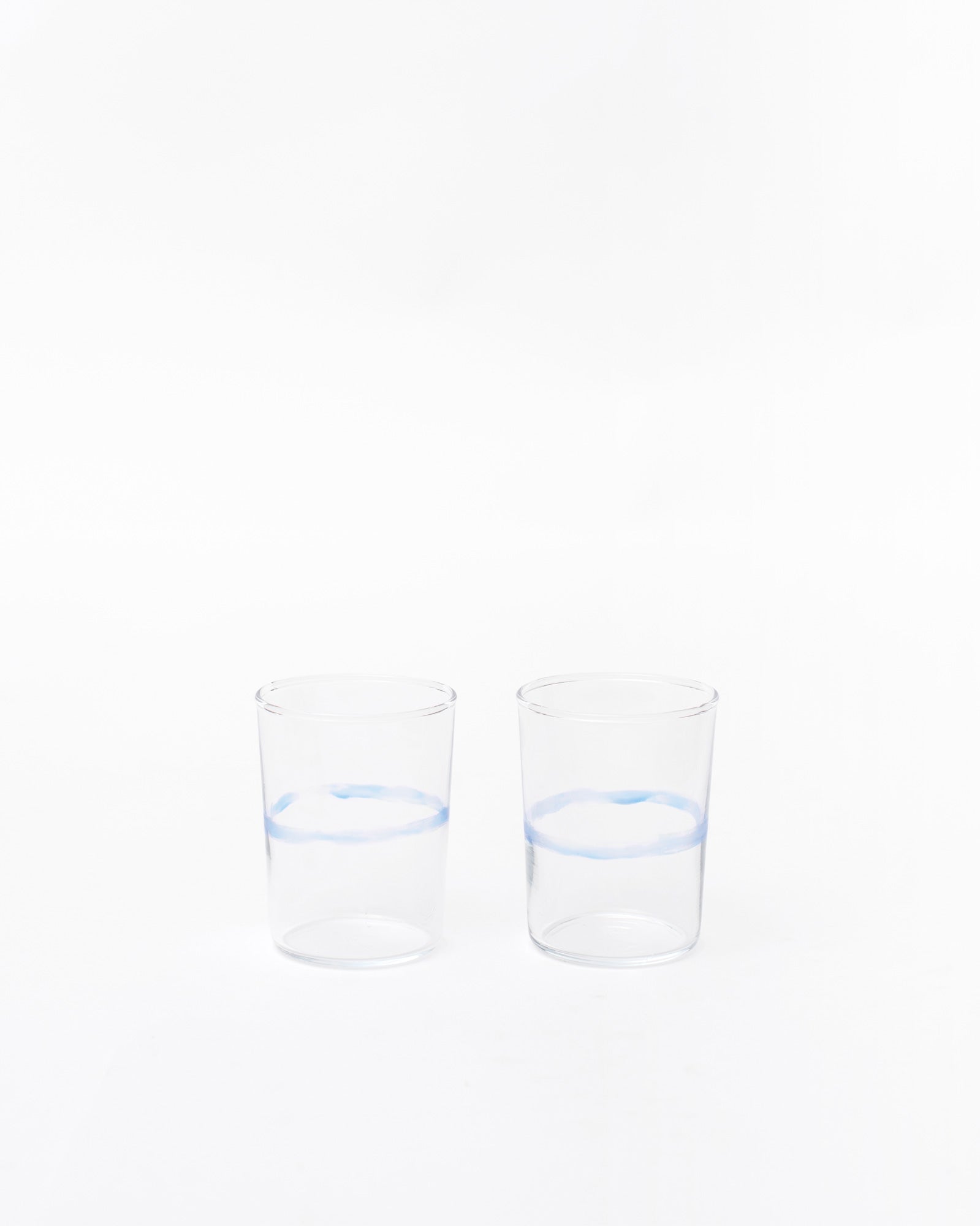 Two glasses with handmade line design next to each other on white studio background