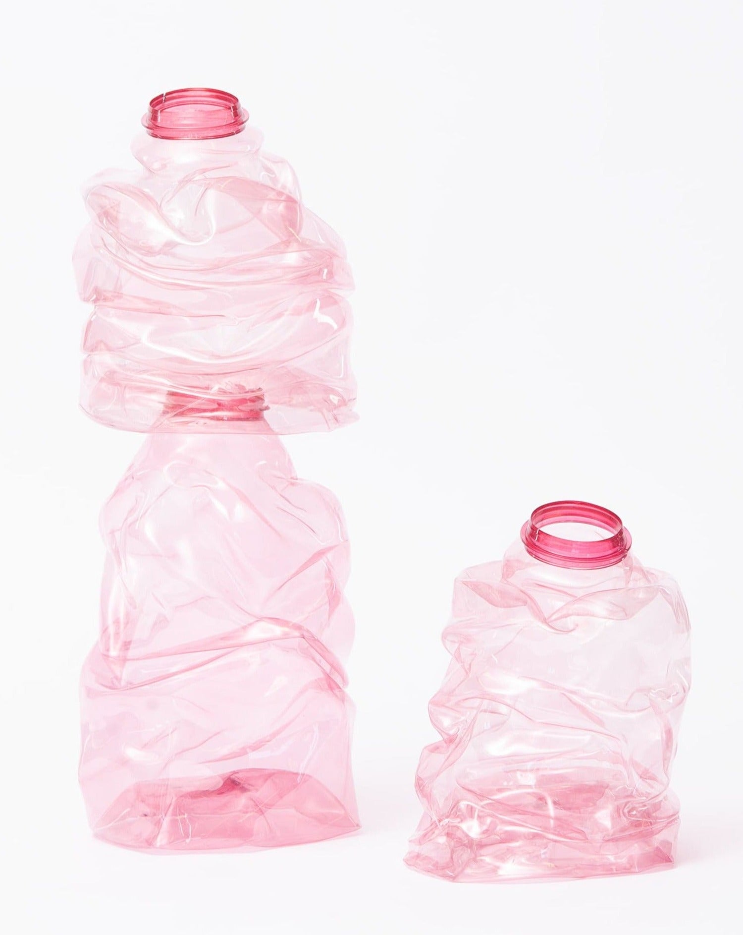 Pink handmade recycled plastic vases placed simultaneously on a white background