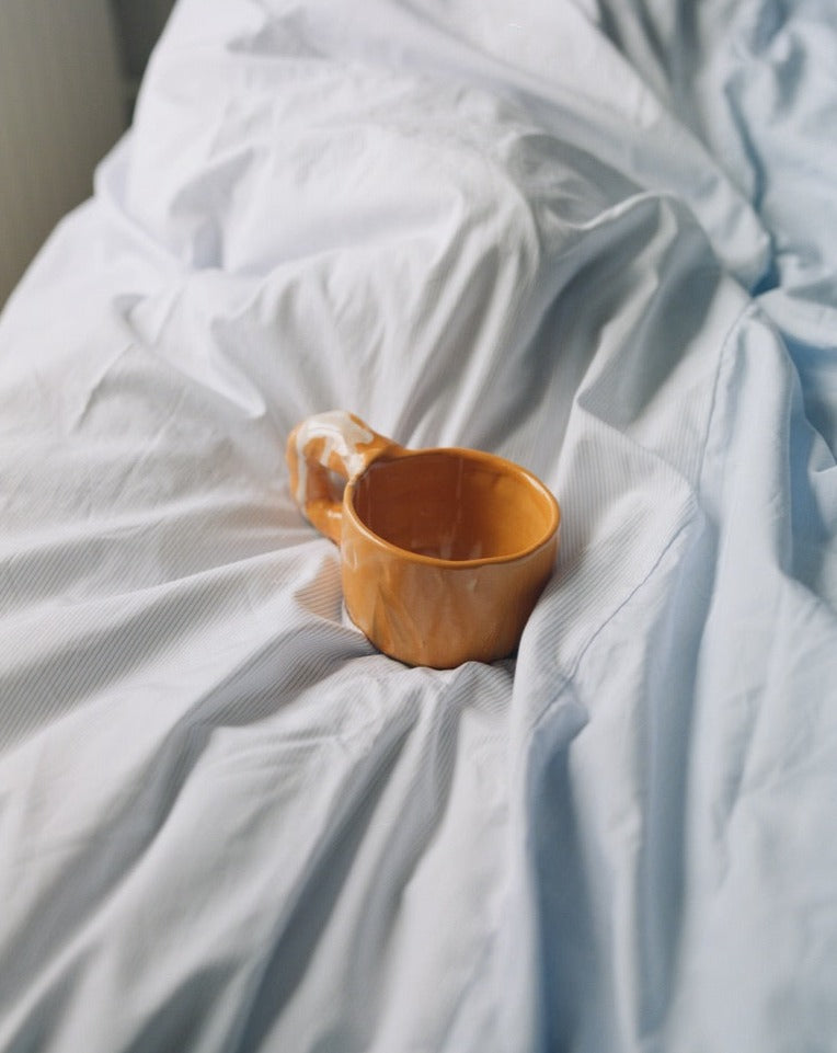 Bed background, orange modern ceramic cup