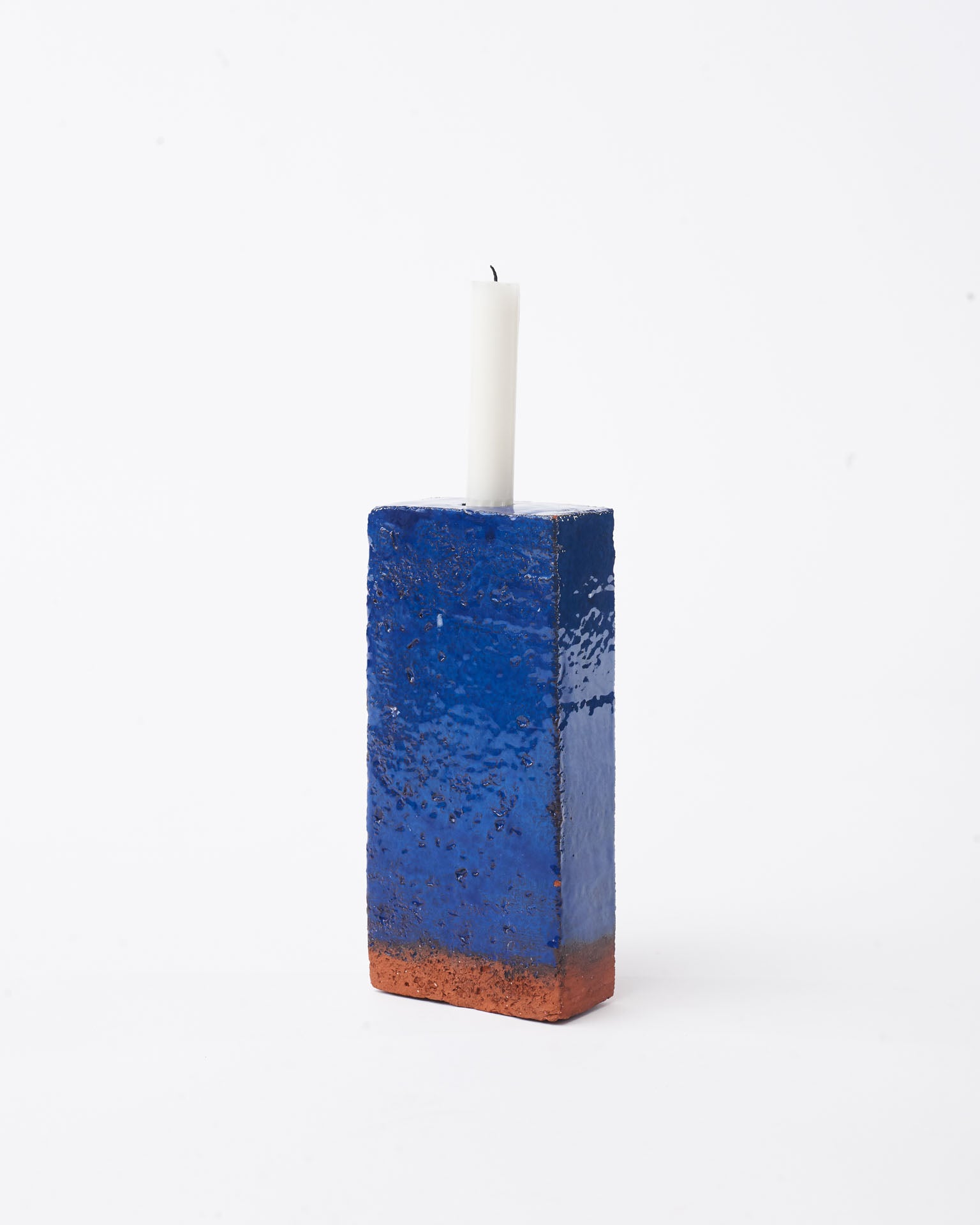 Handmade dark blue brick ceramic candle holder in white glaze in white background