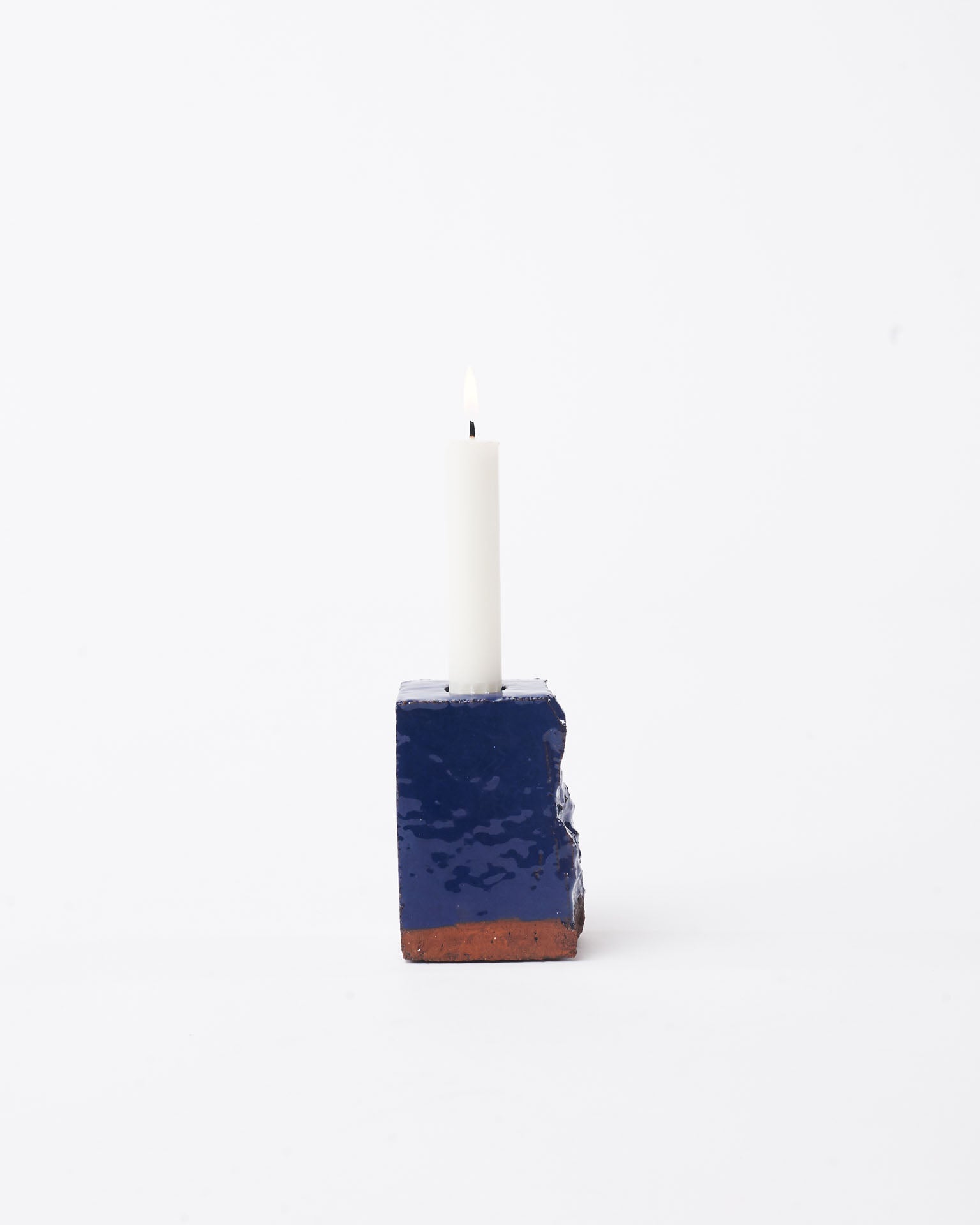 Handmade dark blue brick ceramic candle holder small with candle in the top in white background