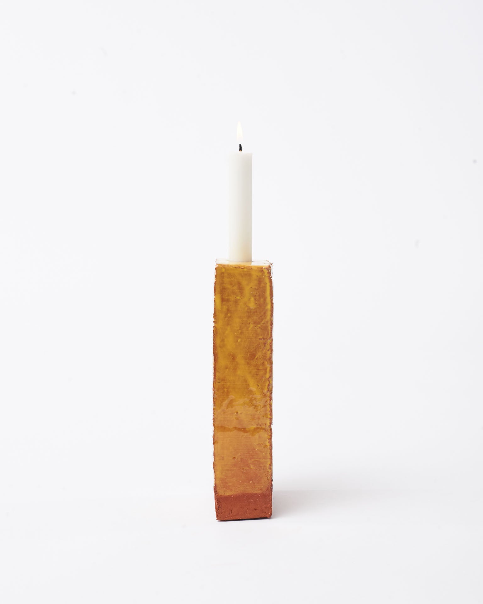Handmade yellow brick ceramic candle holder in white glaze in white background with right side view