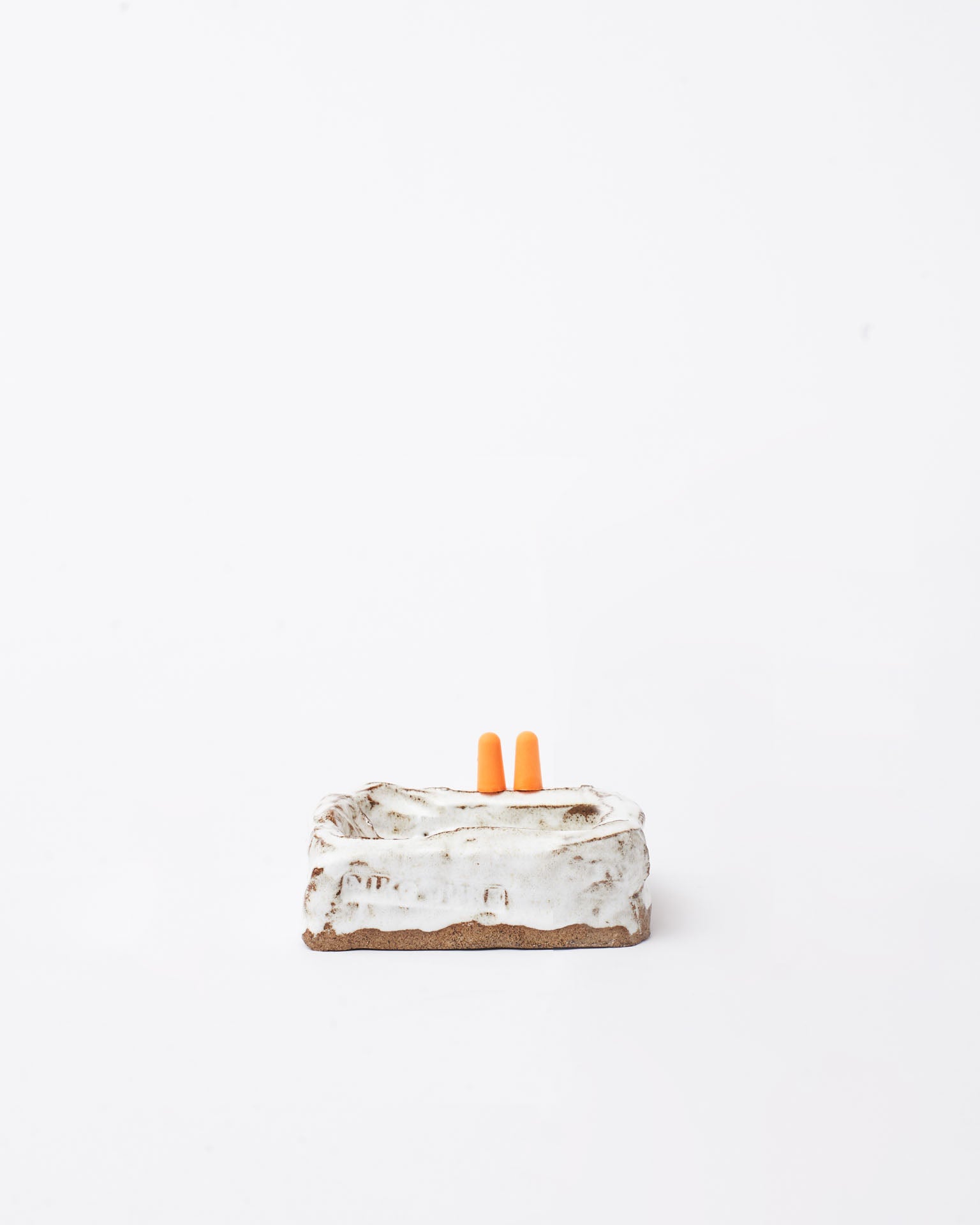 Handmade ceramic organizer object white with two earplug in white background