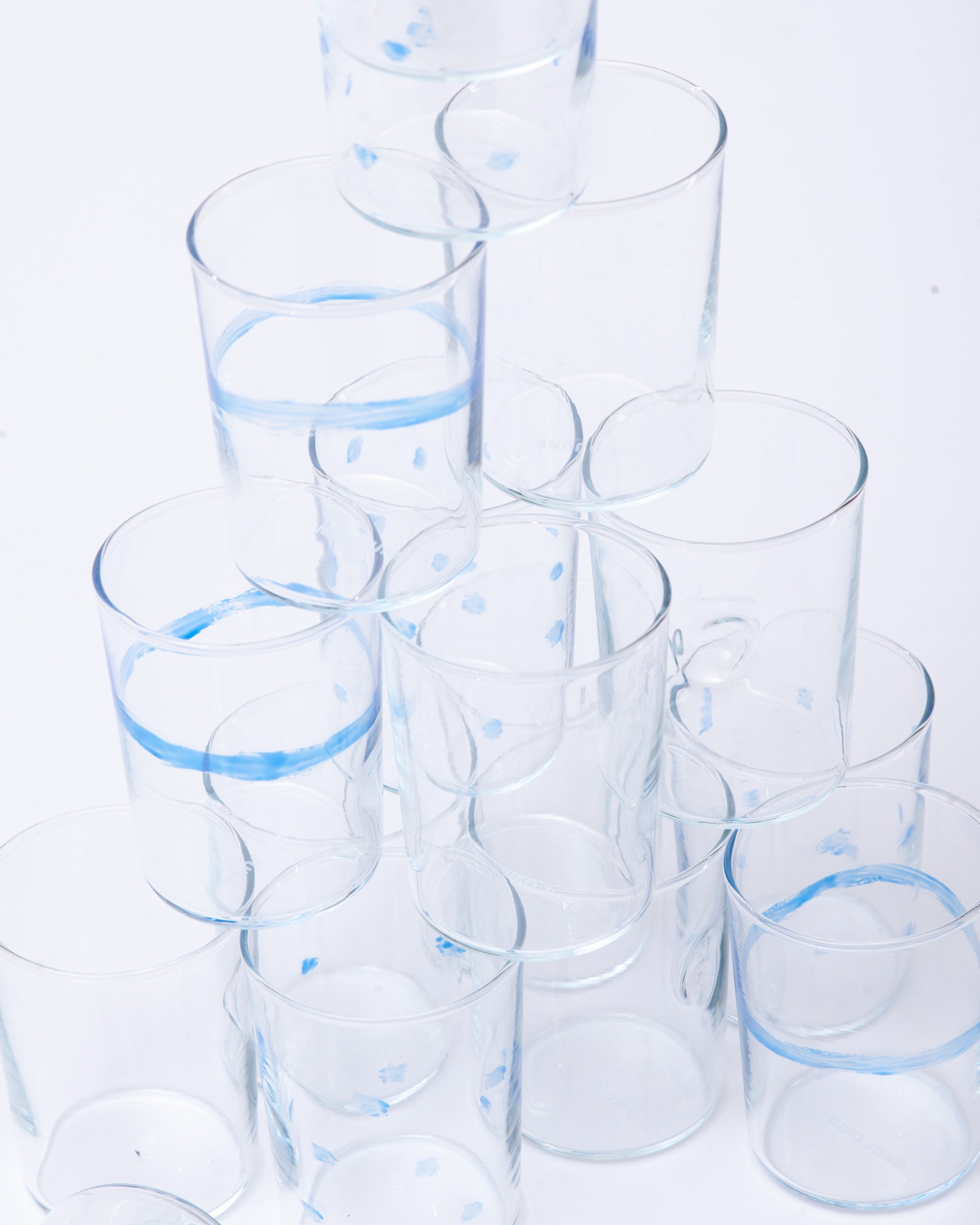 Glasses on top of each other with design of dots, lines handmade on a white studio background