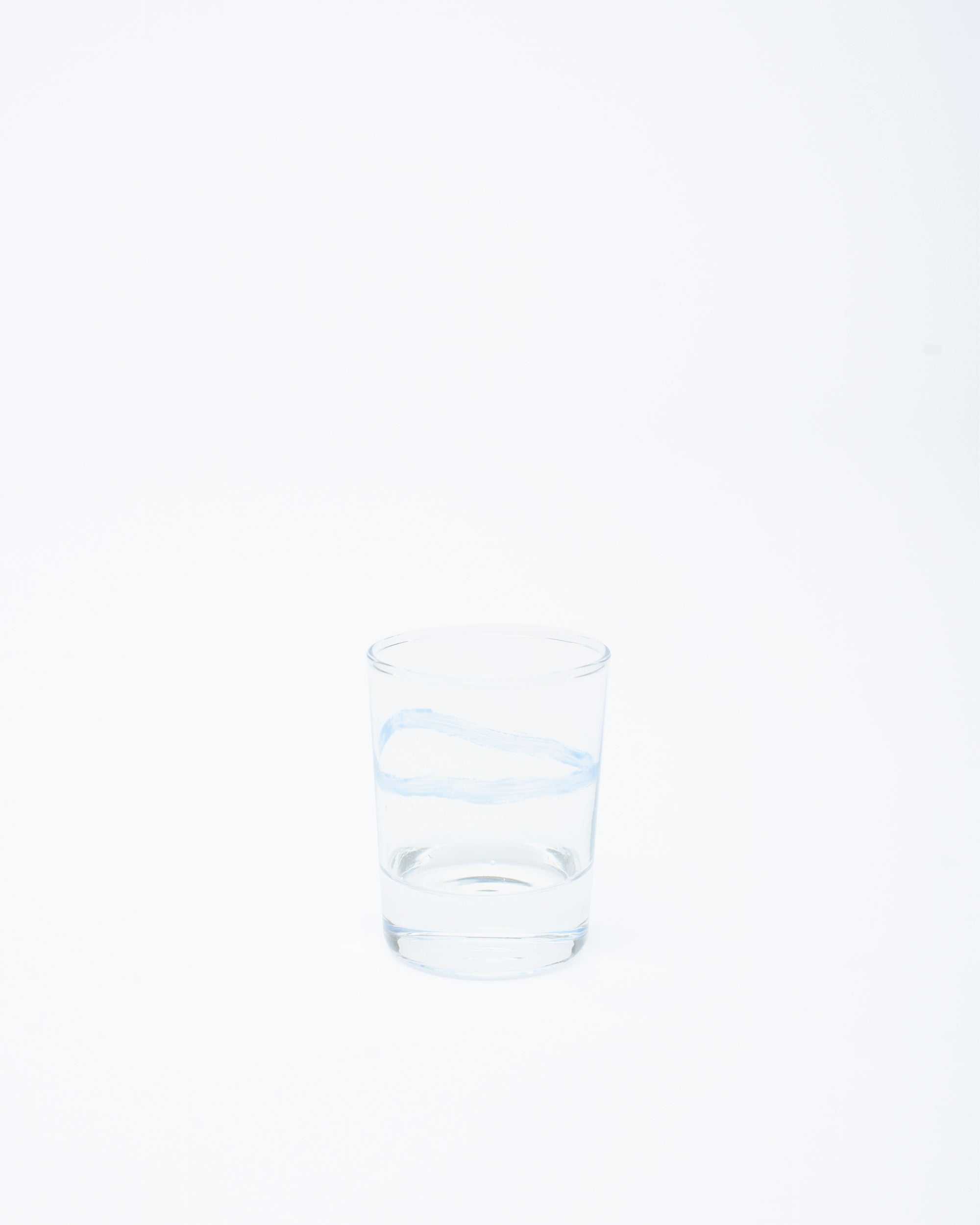Glass with a handmade line design with water on a white studio background
