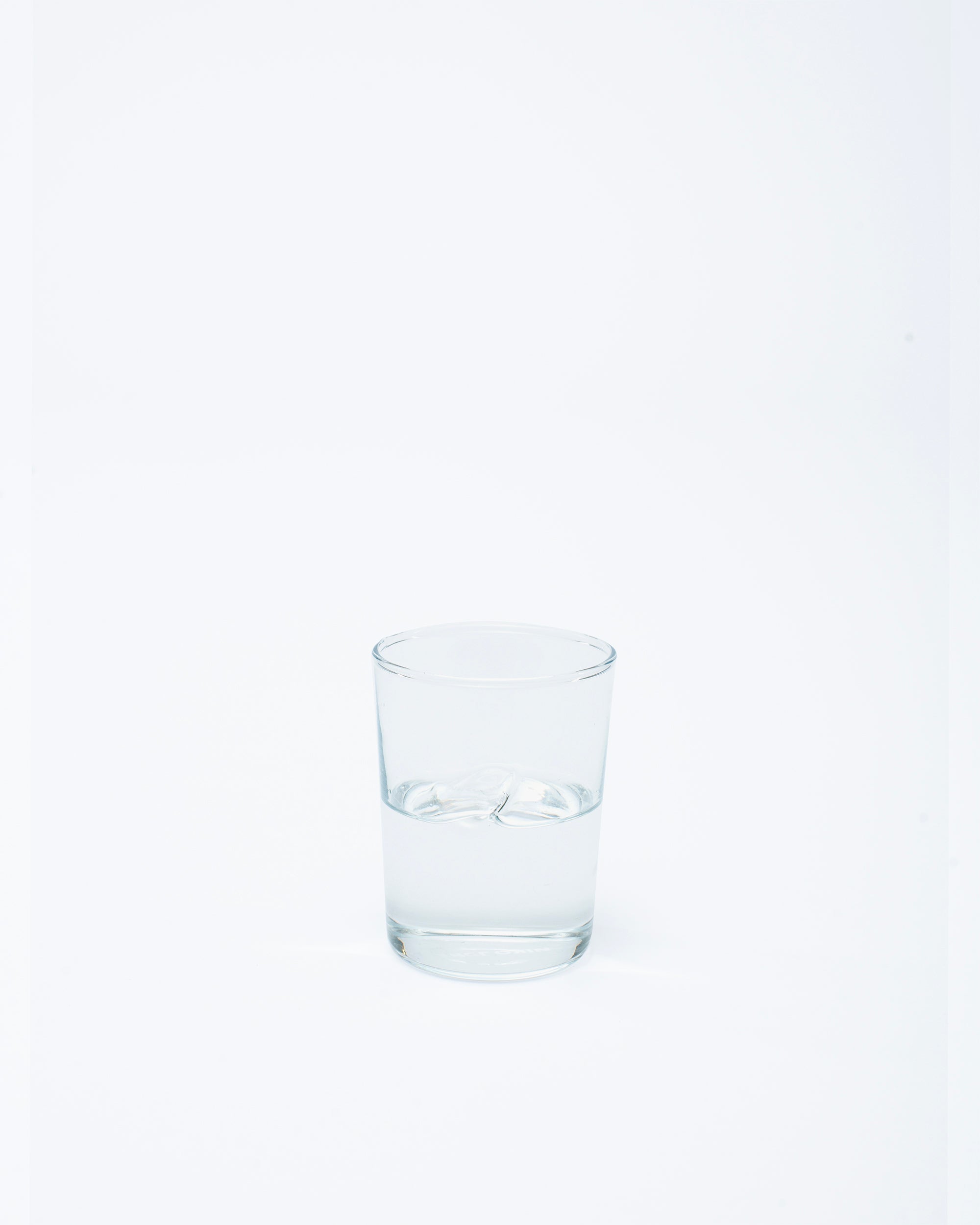 Glass with a handmade dot design with water on a white background