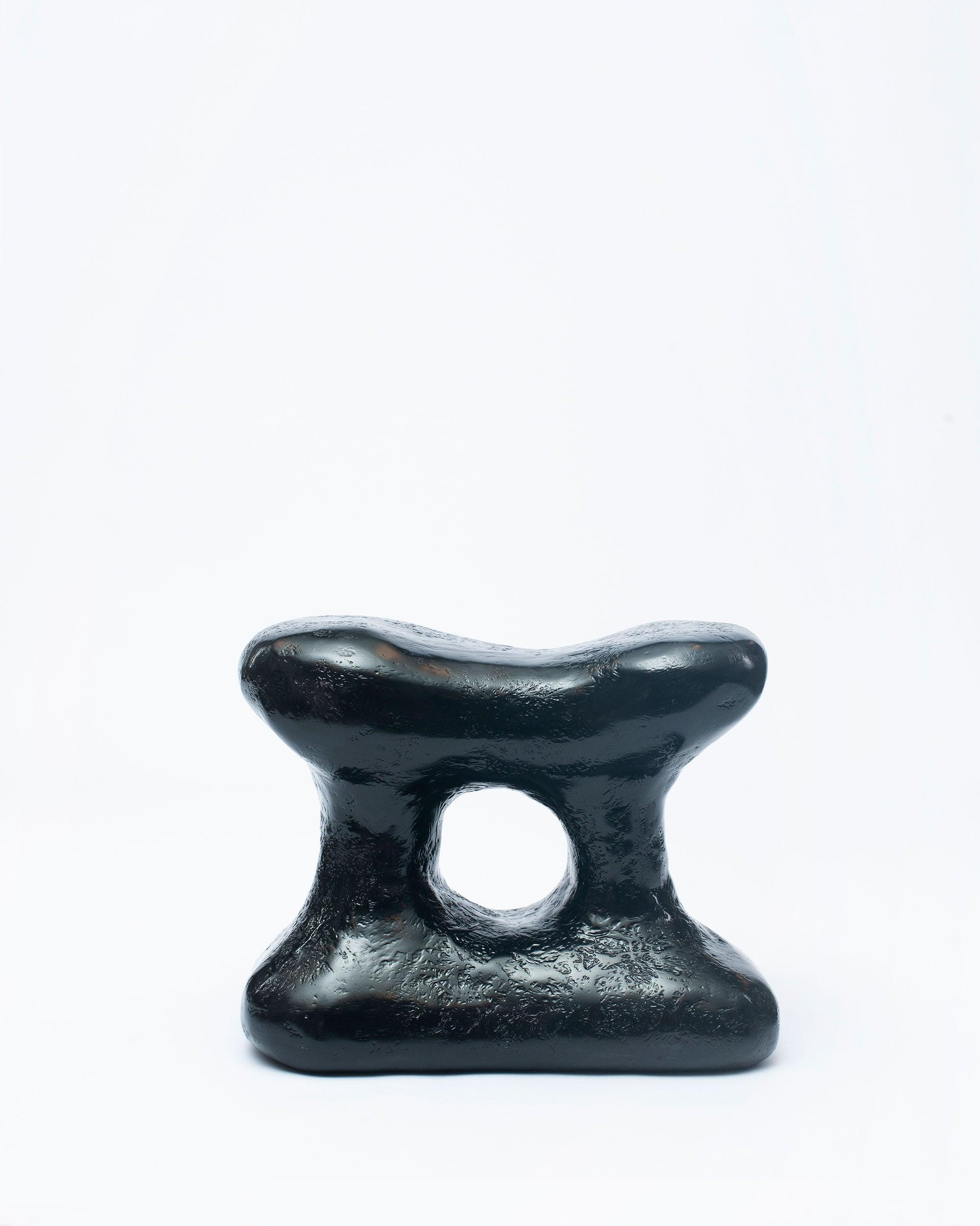 Hand-carved collectible black stool by NIKO JUNE in white background