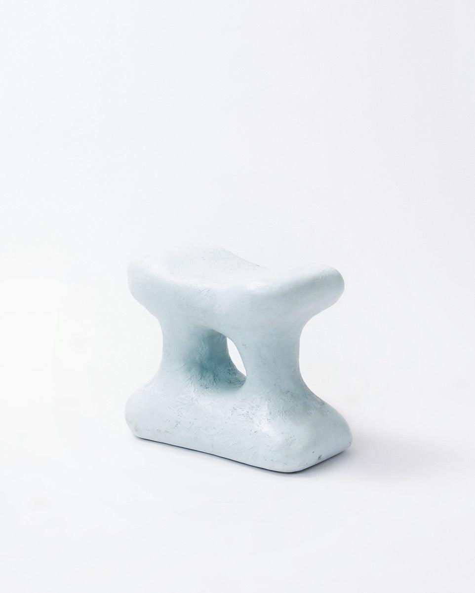 Hand-carved collectible white stool by NIKO JUNE in vertical position in white background