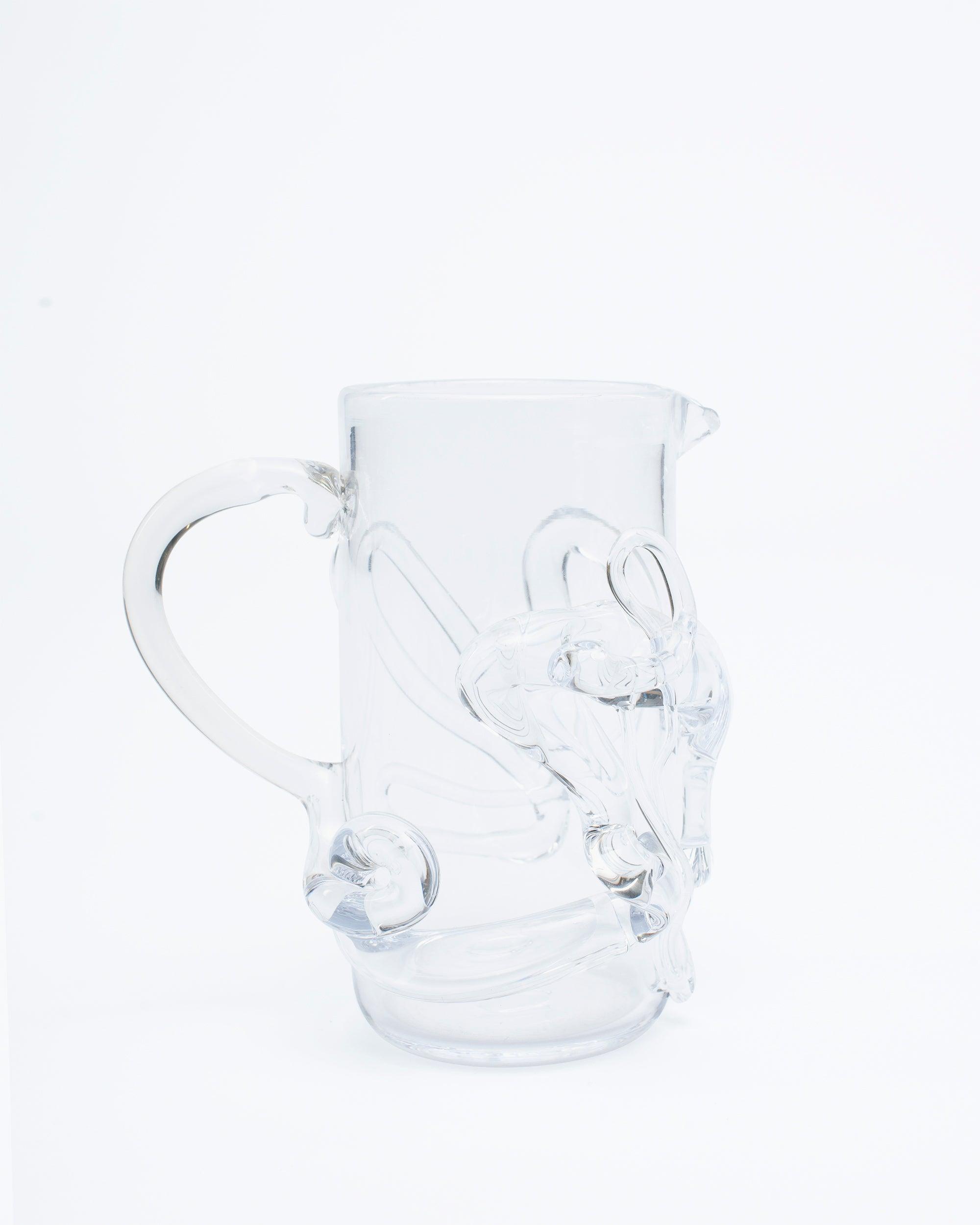 Glass pitcher with melted glass details with handle on right side on light focus background