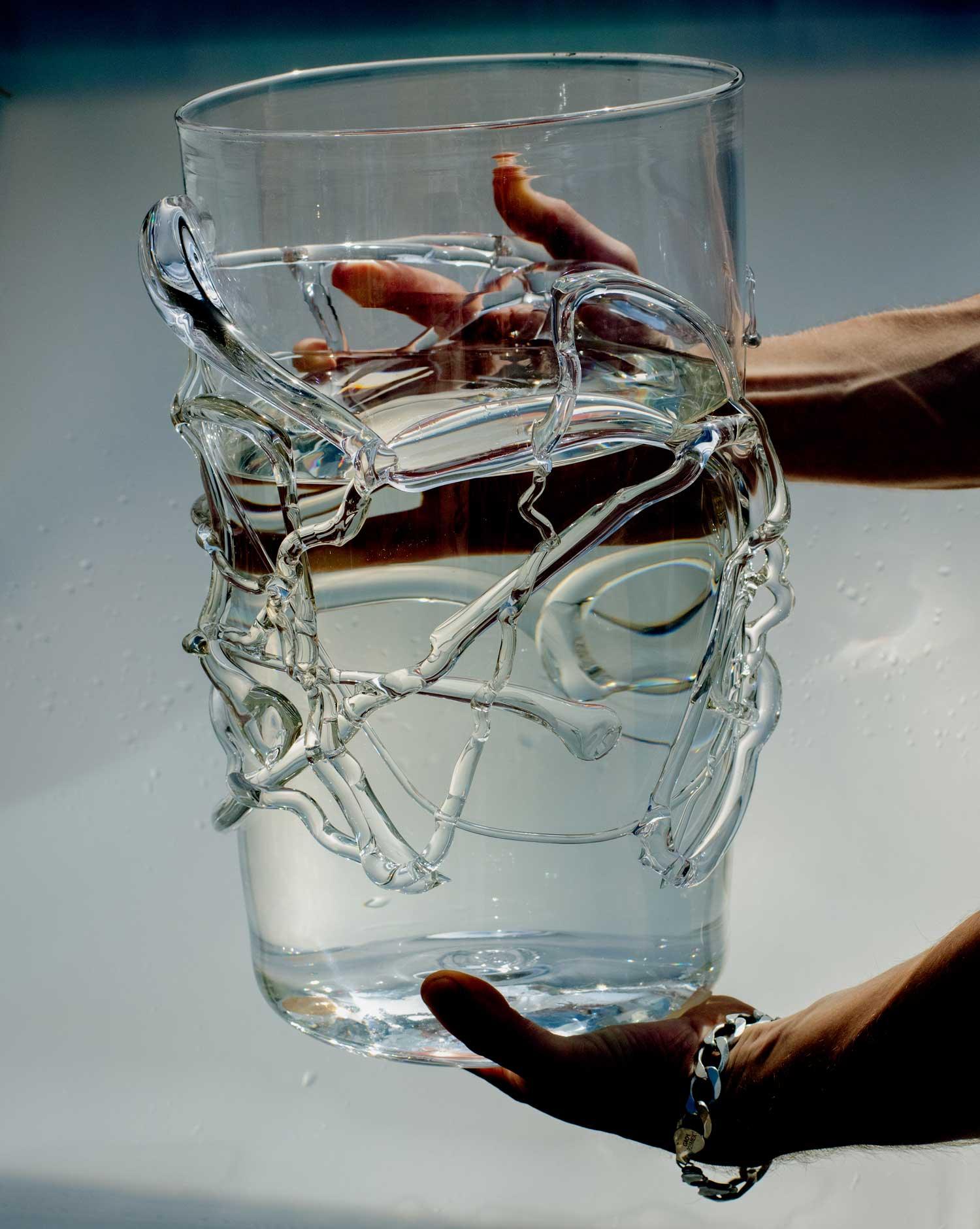 Hands holding a large vase with melted glass details white background.