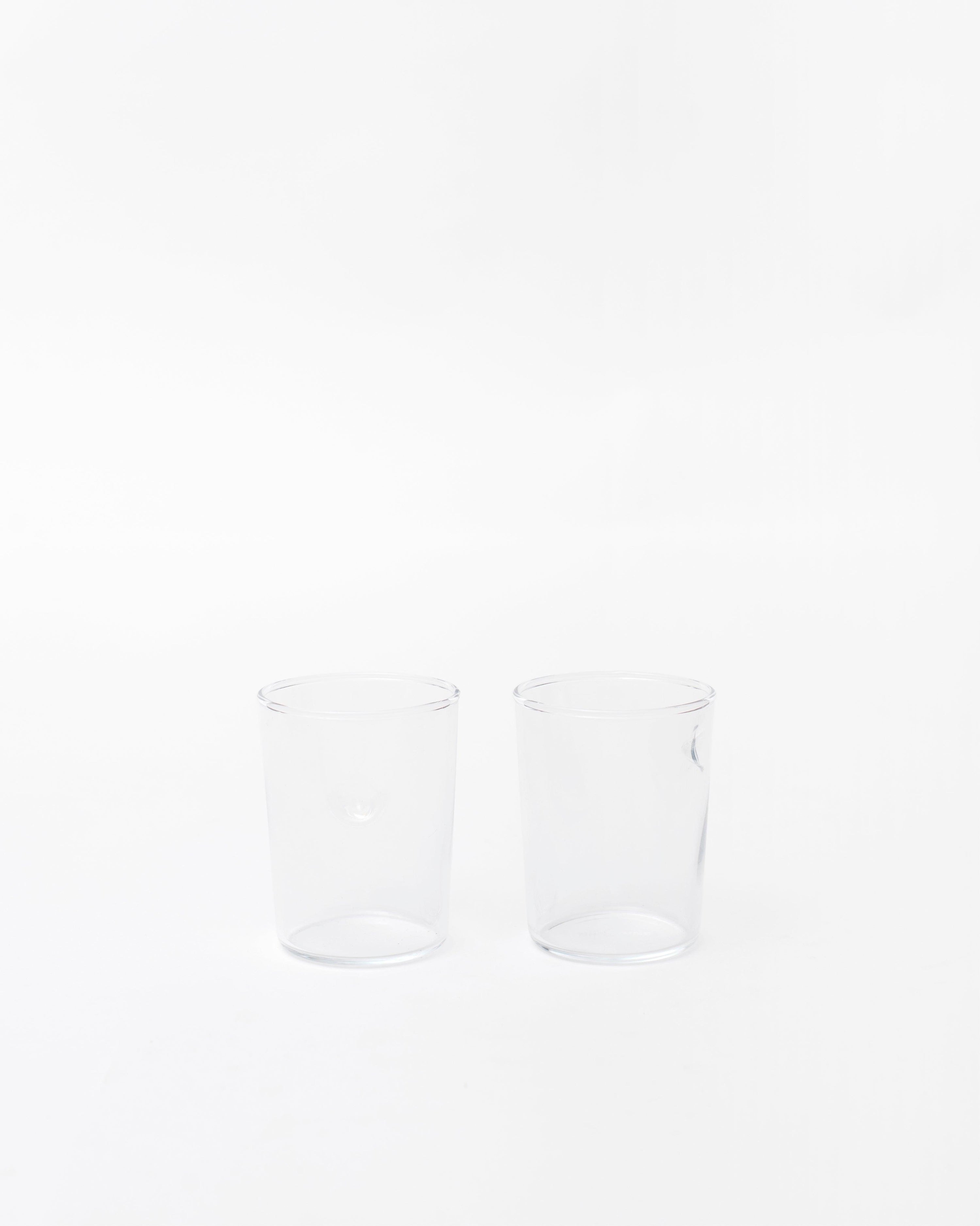 Two glasses with a handmade dot design next to each other on a white studio background