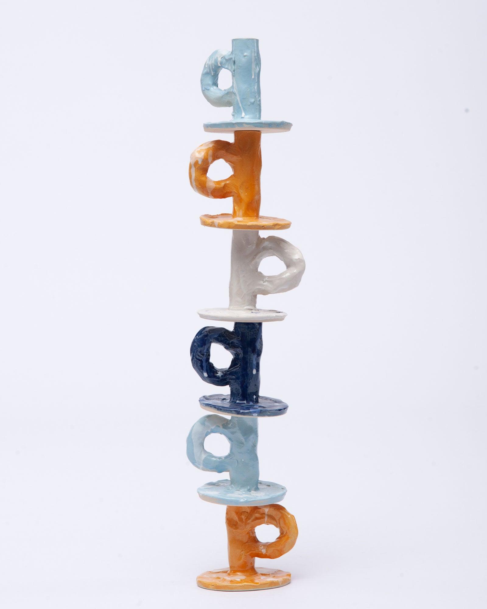 Handmade six candlesticks of different colors one on top of the other on white background