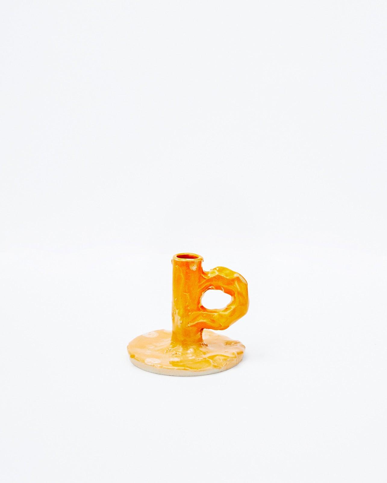 Handmade orange candlestick with handle with front view on a white background
