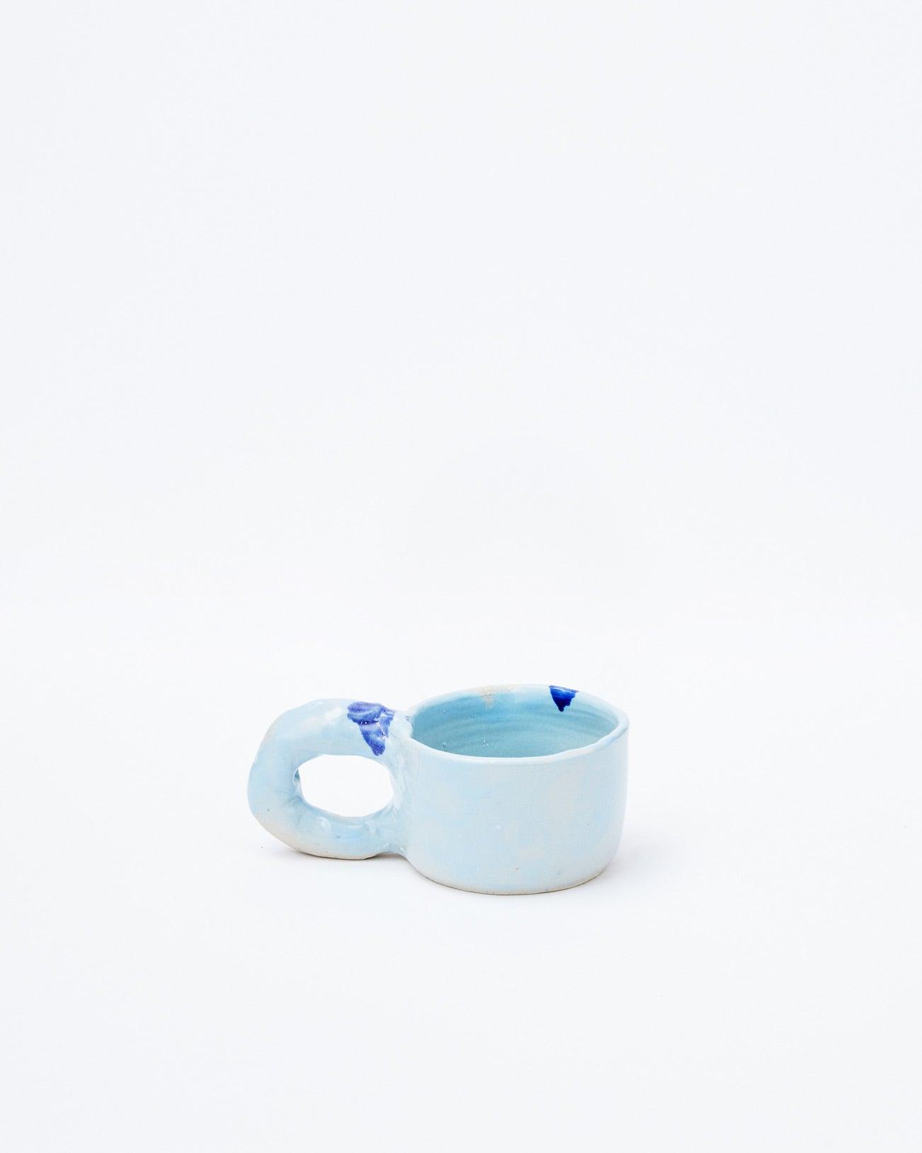 White background, light blue modern ceramic cup with handle in left position
