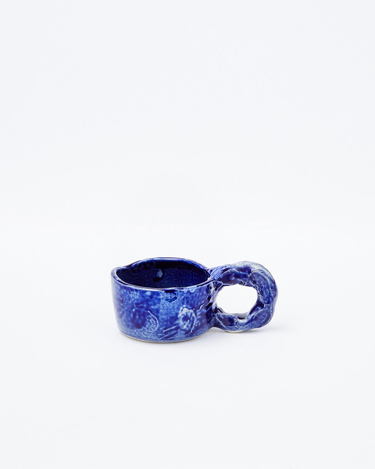 White background, dark blue modern ceramic cup with handle in right-hand position