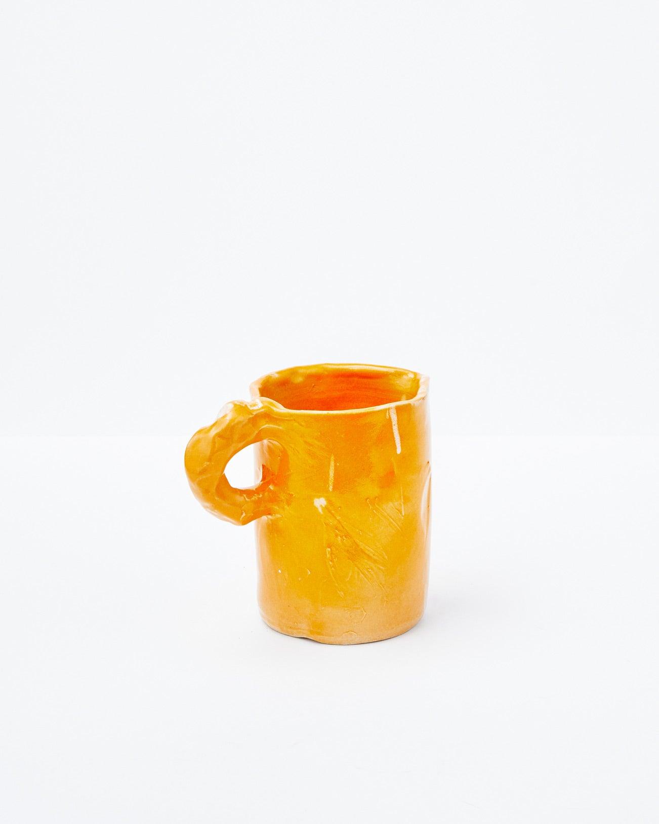 Orange modern ceramic pitcher with diagonal handle on a white background