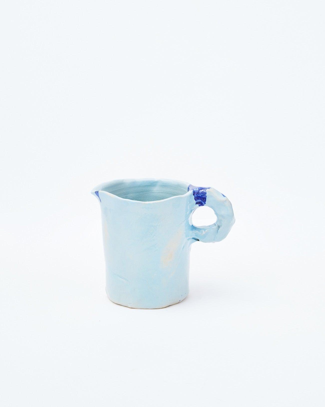 Light blue modern ceramic pitcher with left-handed handle on a white background