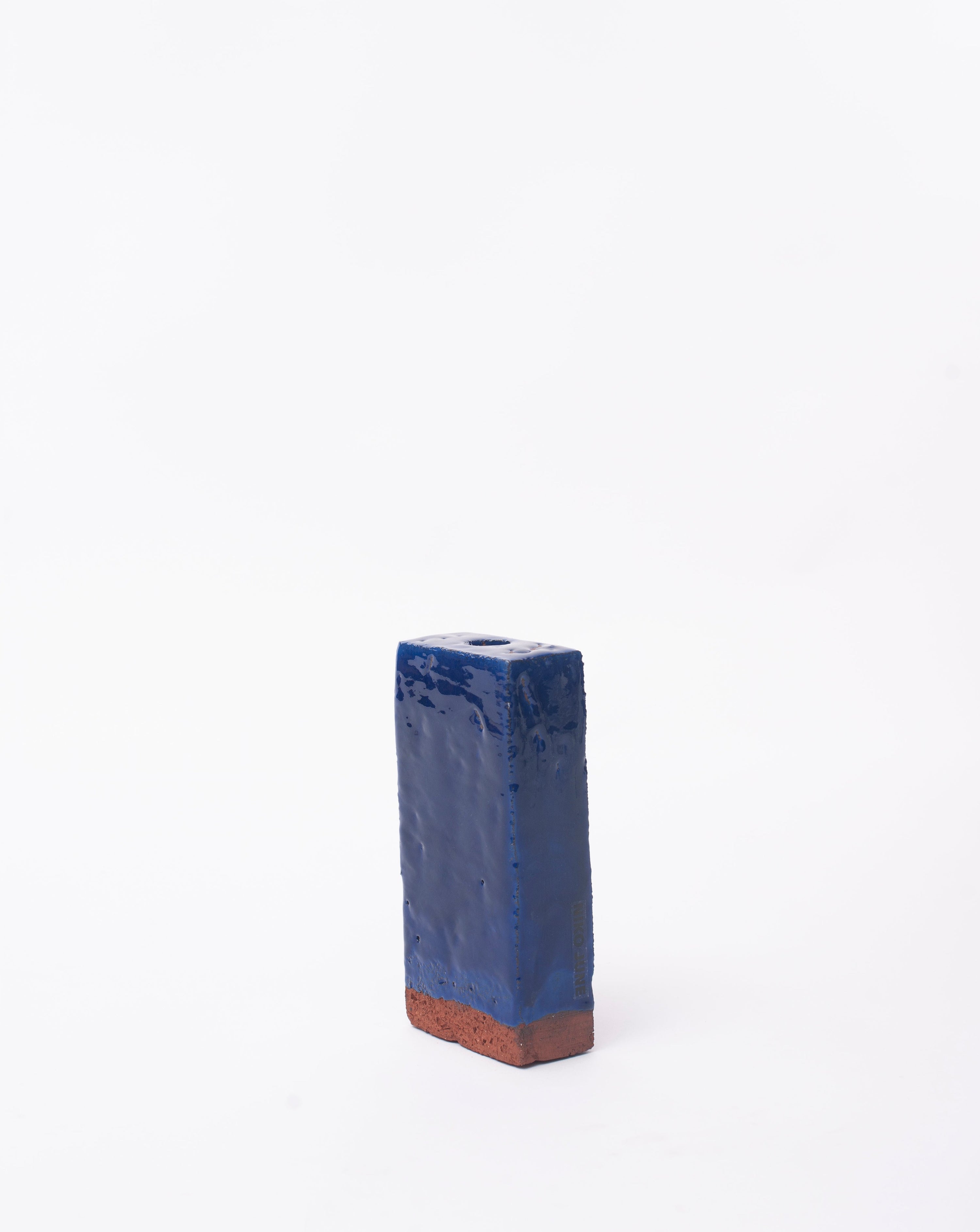 Handmade dark brick ceramic candle holder in white glaze in white background with right side view