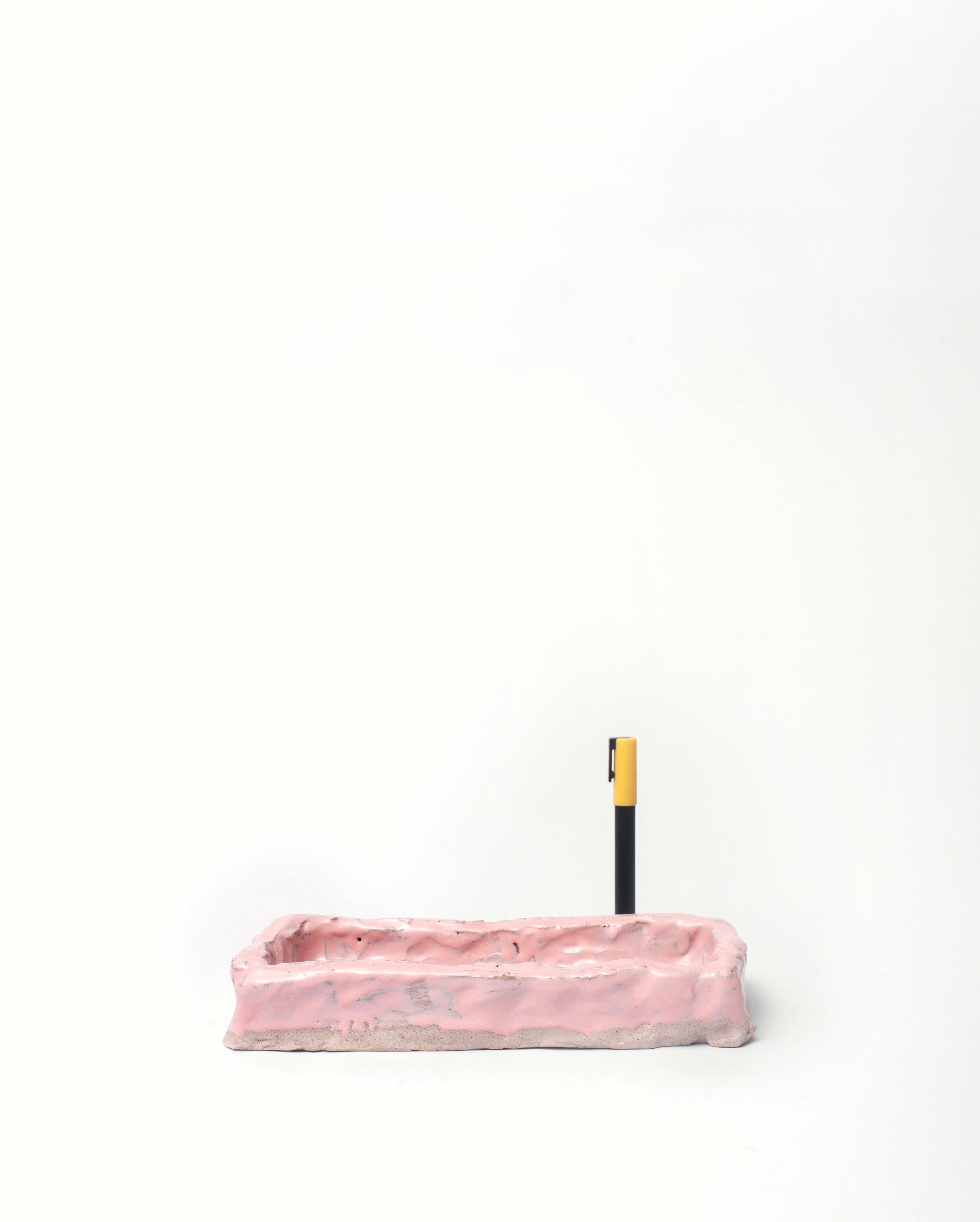 Handmade ceramic organizer object in pink with pen in the right corner white background