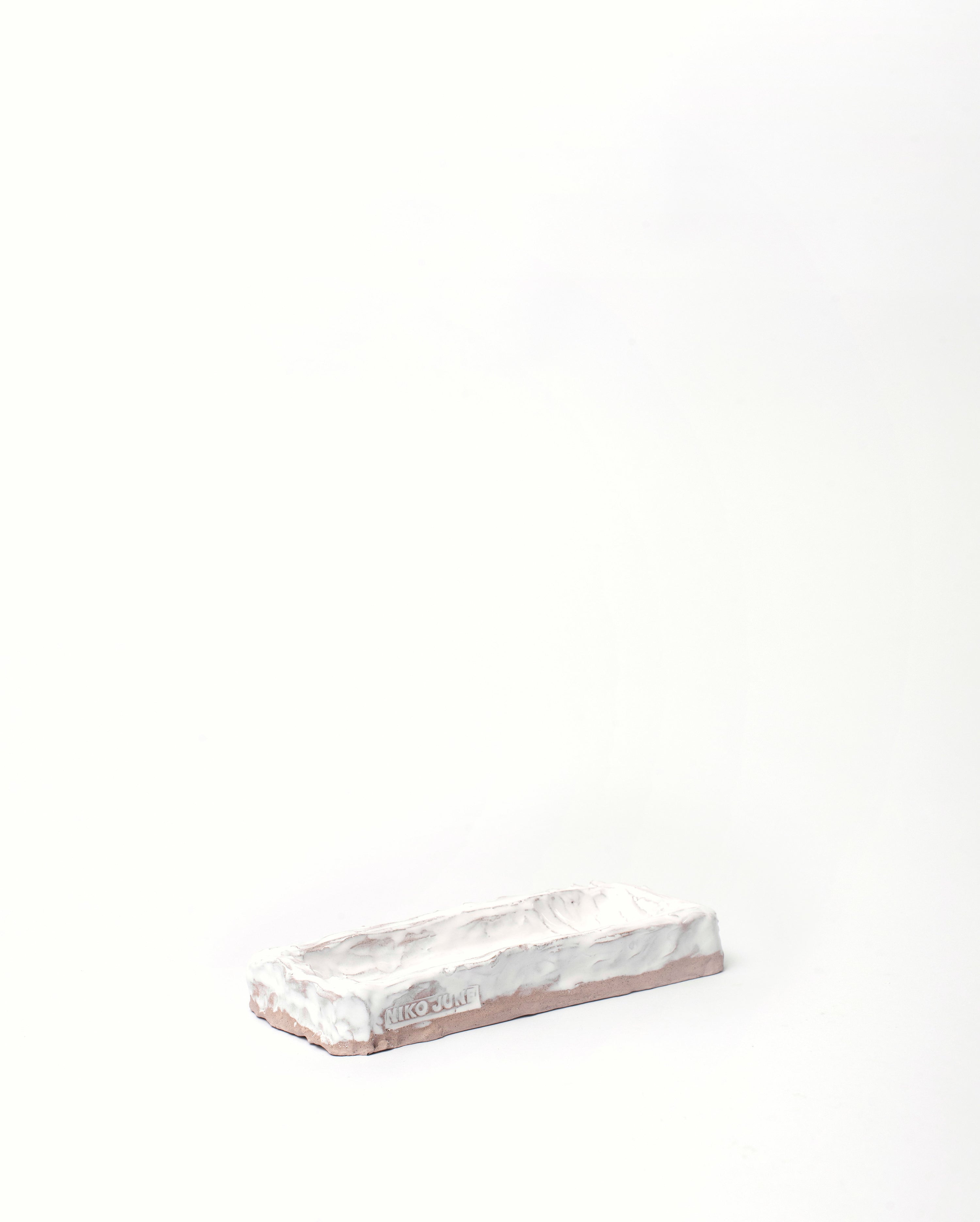 Handmade ceramic organizer object in white tilted white background