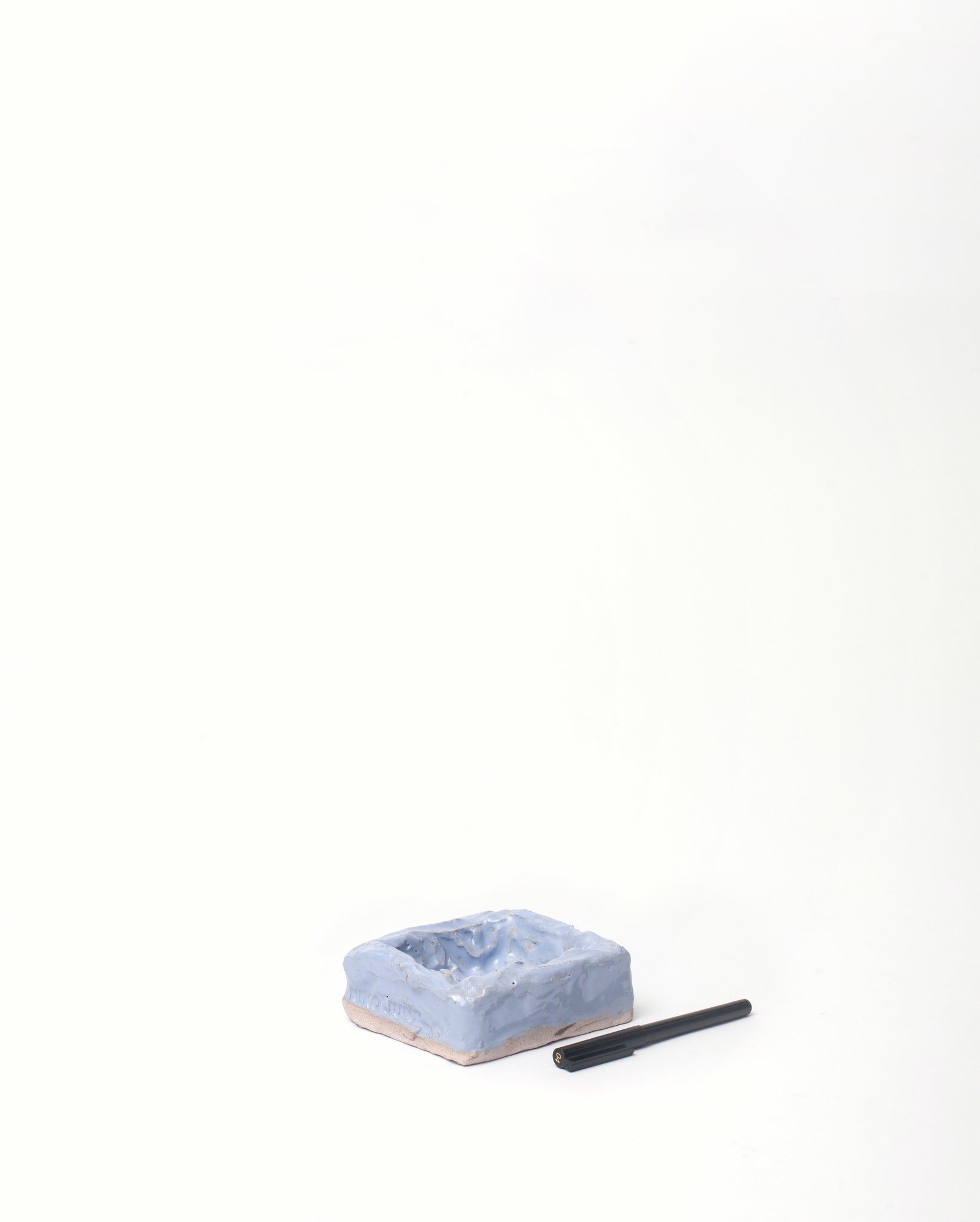 White background, Handmade jewelry ceramic organizer light blue base in slanted position with black pen on the side