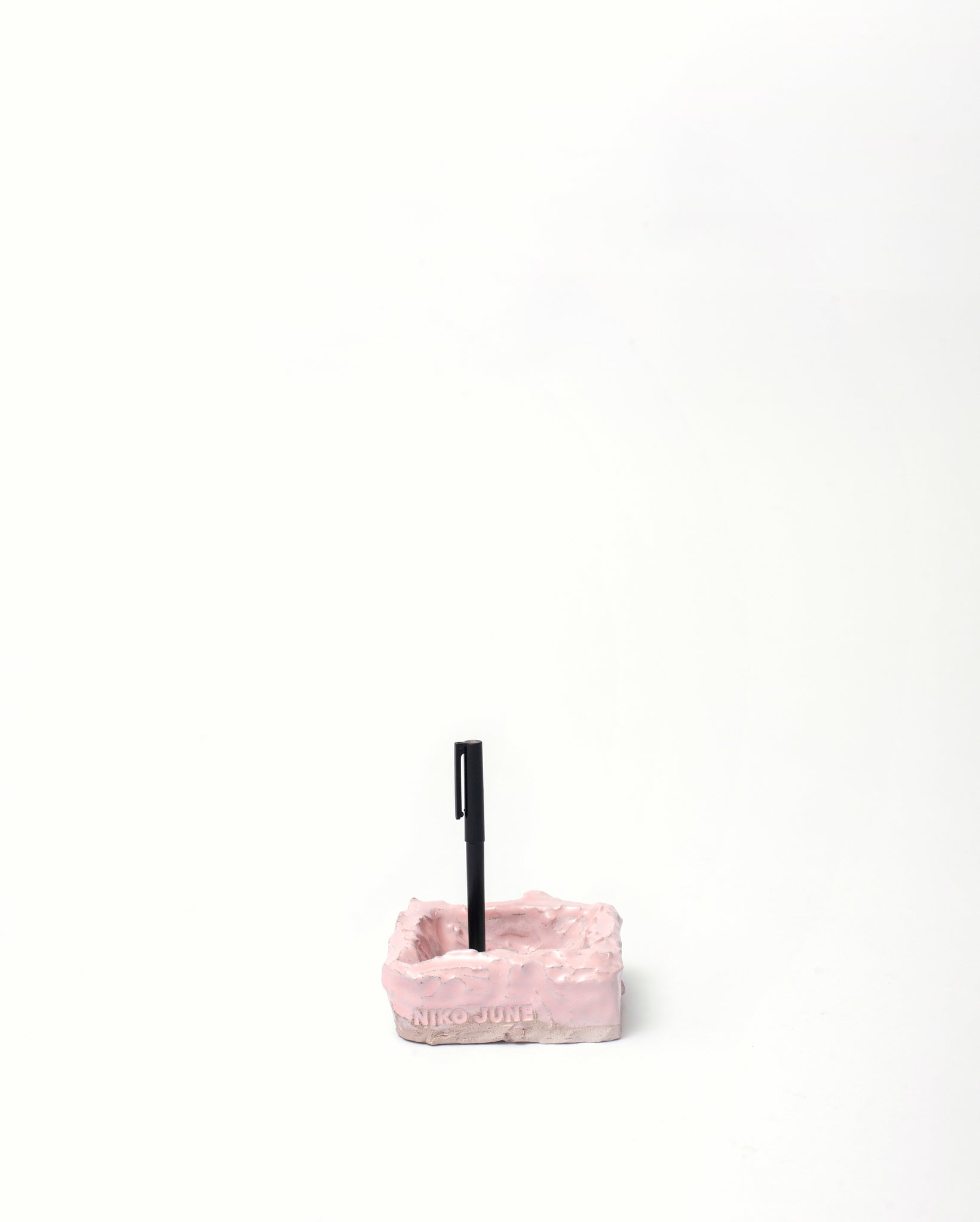 White background, Handmade jewelry ceramic organizer pink with black pen inside in vertical position