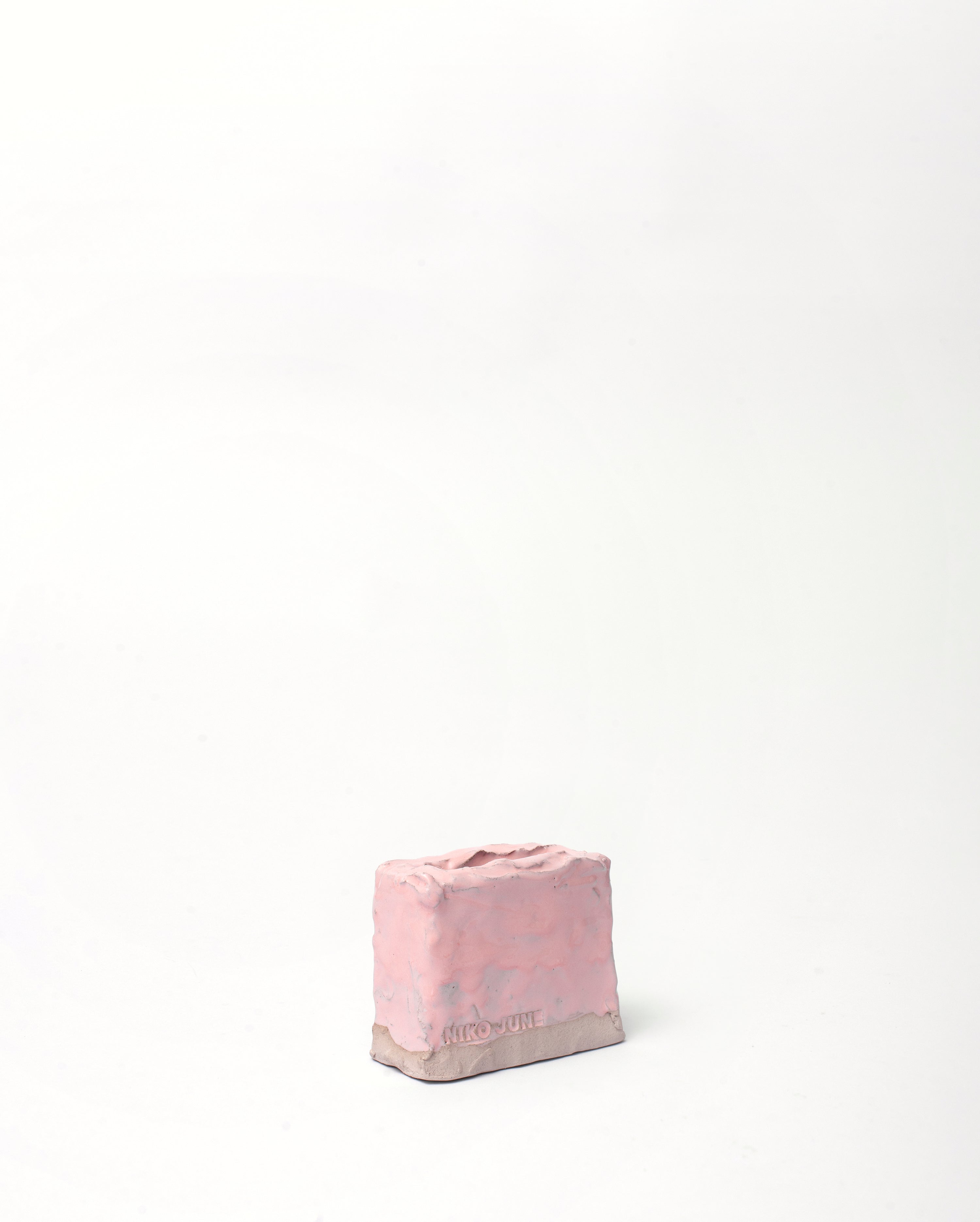 Handmade ceramic organizer object in pink glaze in left leaning position in white background